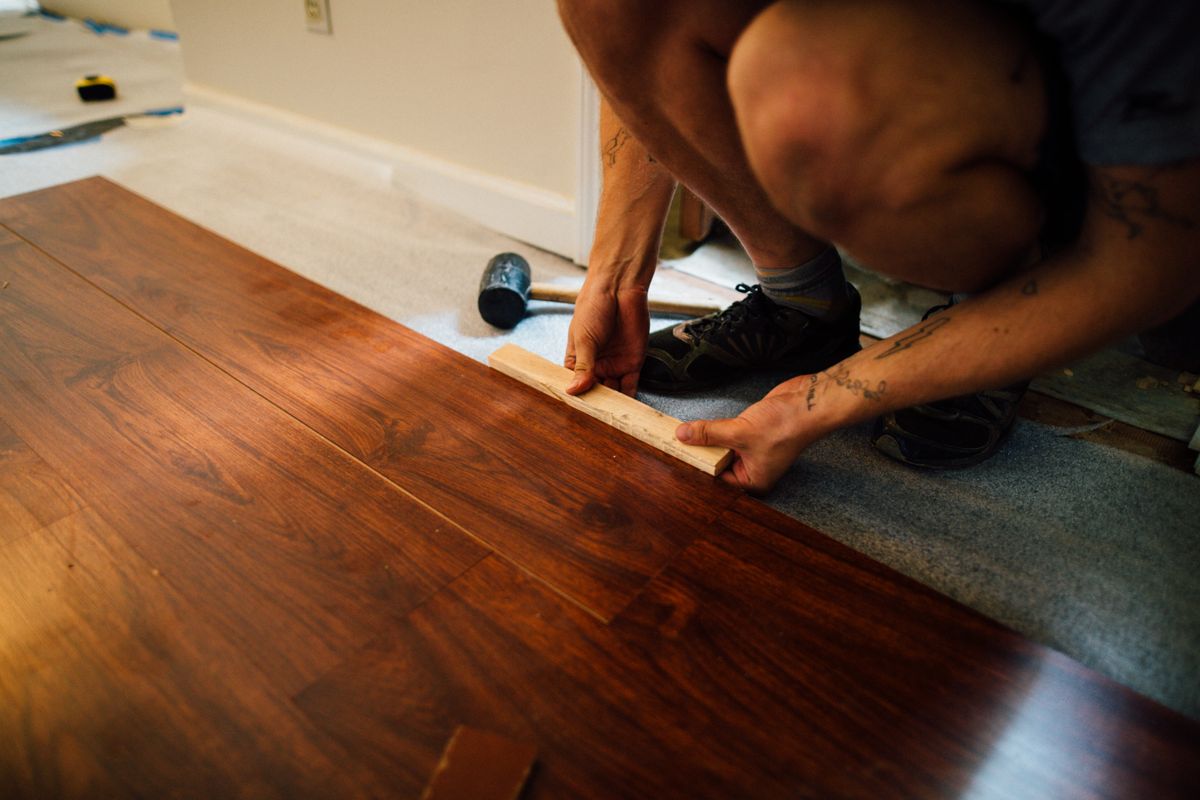 Installer Tapping a Wood-Look Floating Plank into Place