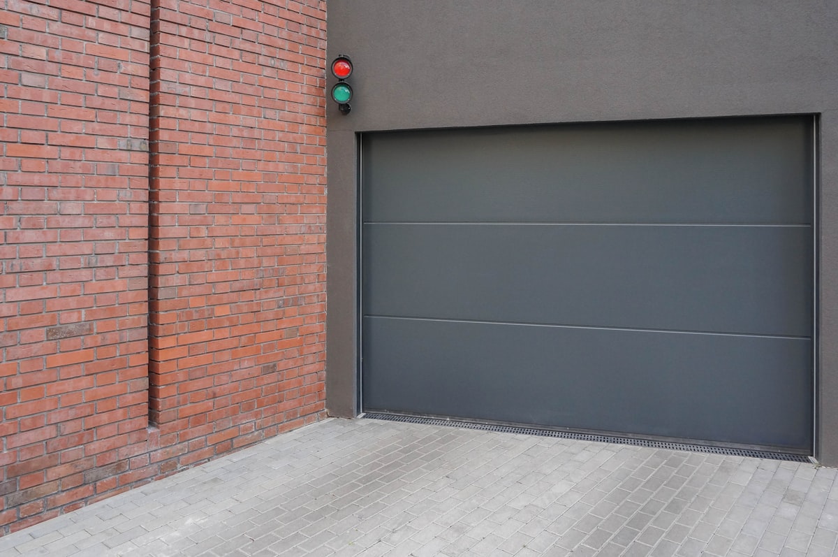 Charcoal Flush Sectional Garage Door on a Modern Brick-and-Stucco Building