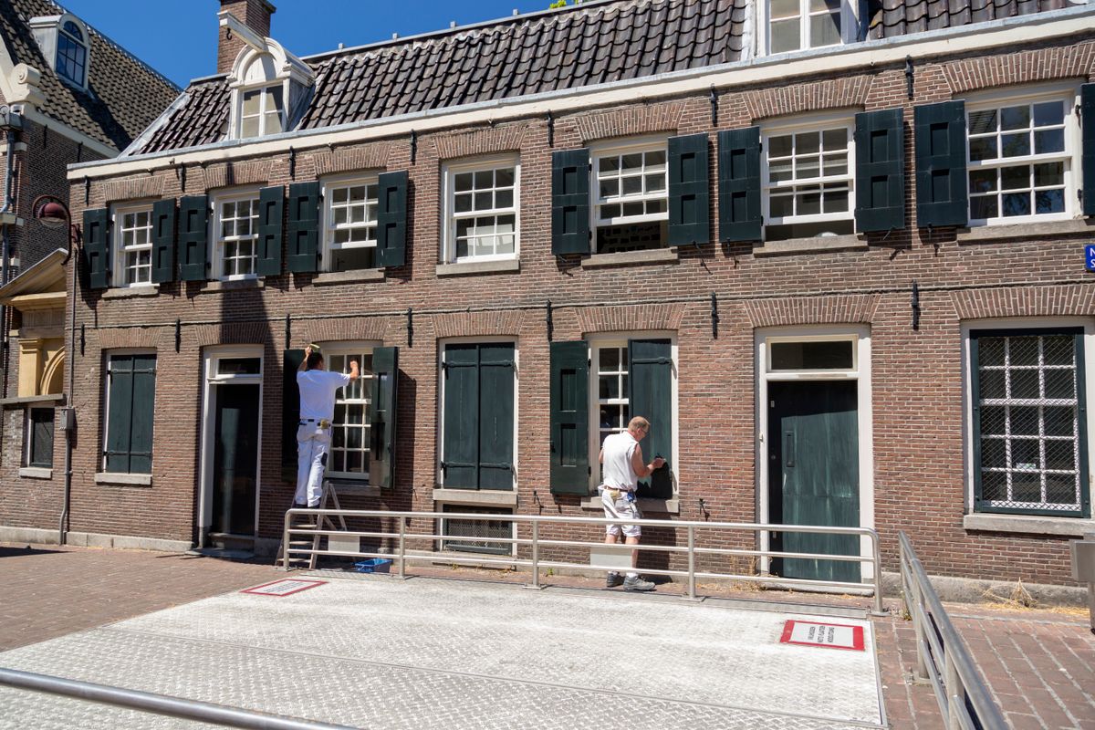 Two Painters on a Ladder Repainting a Brick House Facade
